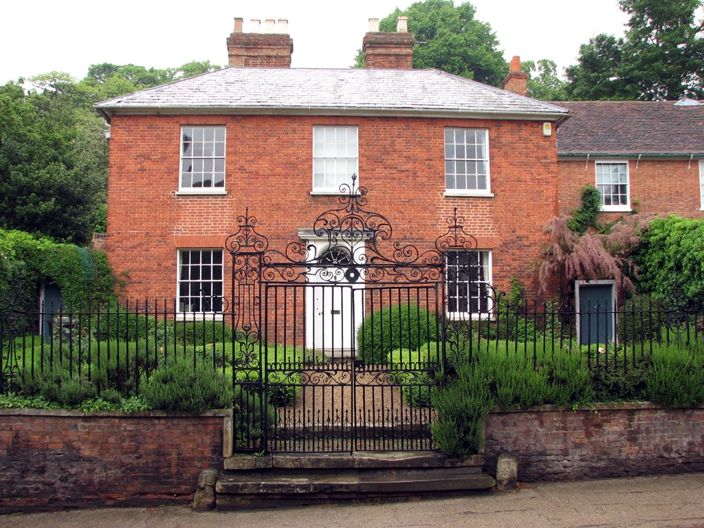 A red-brick Georgian house with sash windows and wrought-iron gates
