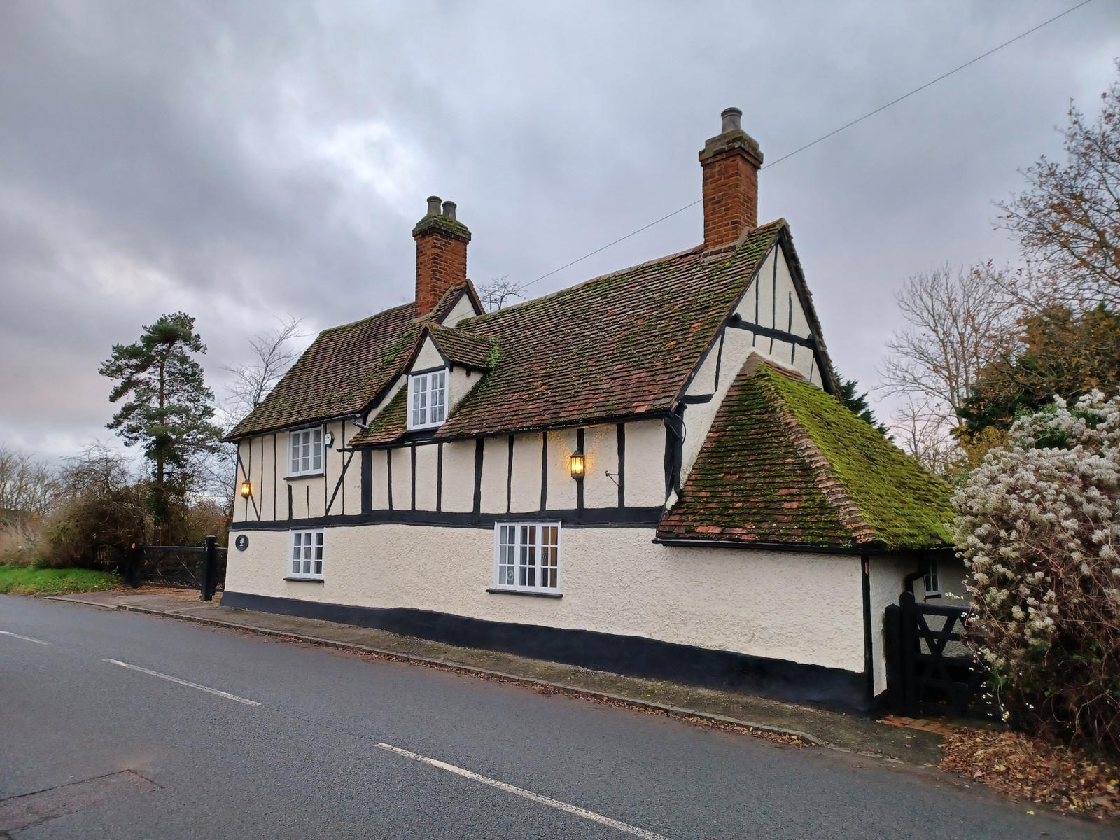 A traditional timber-framed cottage with tiled roofs and tall brick chimneys